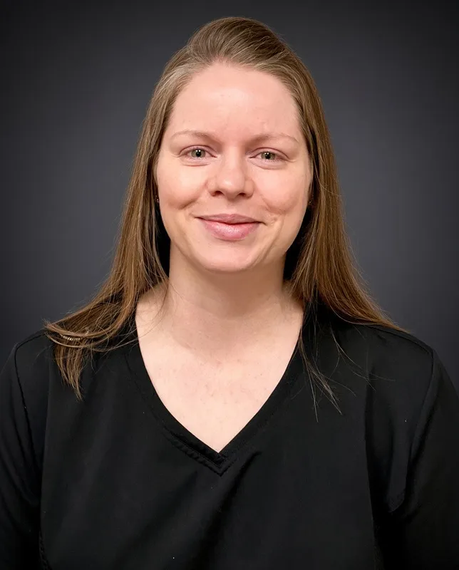Headshot of a smiling female dental staff member with long blonde hair wearing a black V-neck top